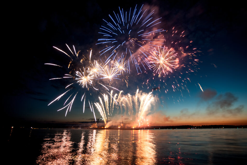 Holiday fireworks above water with reflection on the black sky background ok